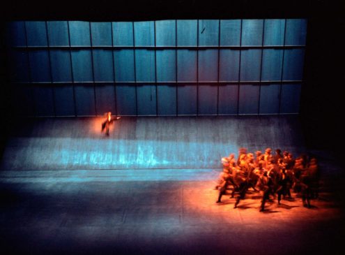 A dark stage with a group of dancers under a spotlight.