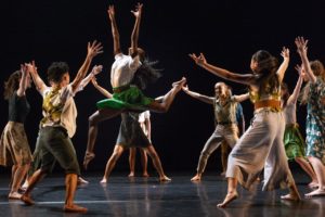 A circle of young dancers surround a single dancer