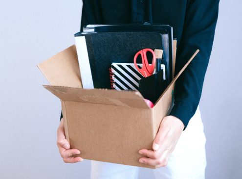 A person holding a box of office supplies