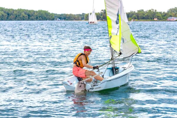 Young boy operating a sailboat on the Toronto waterfront