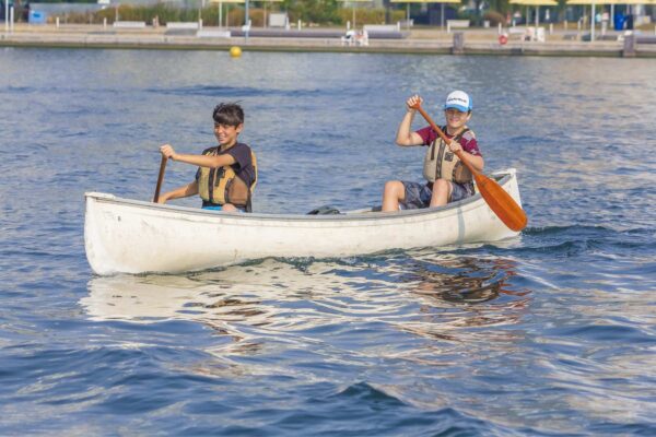 Two kids in canoes on the water