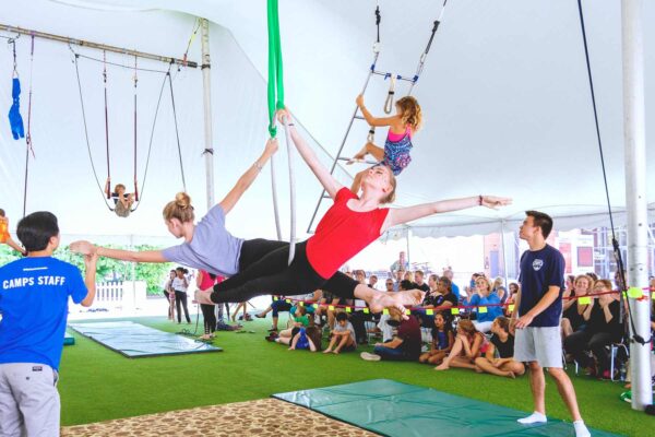 Group of children doing circus acrobatics inside a white tent