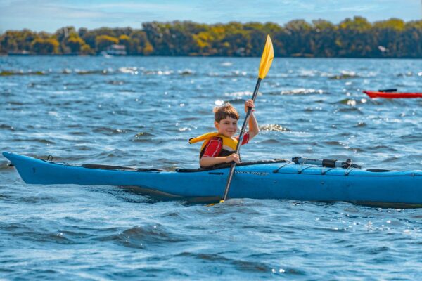 Young boy paddling a kayak on a lake