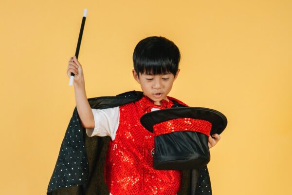 Young child wearing a cape and holding a magic wand