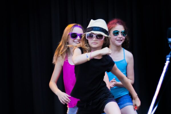 A trio of kids playing pop star on stage