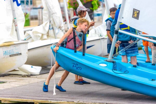 Kid moving their sailboat into the water