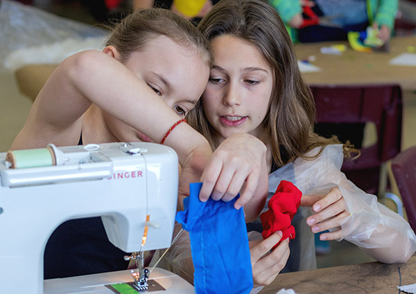 Two kids work at sewing machine