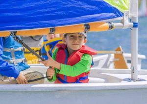A kid in their sailboat on the water