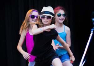 A trio of kids playing pop star on stage