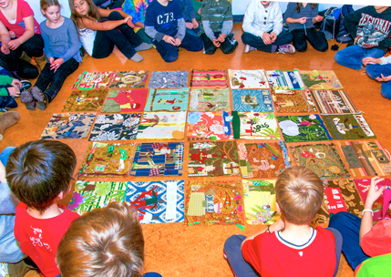 Students sit around a group of artwork on the floor