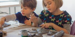Two young students working on clay crafts in a classroom