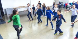 A group of students and teacher dancing in a classroom