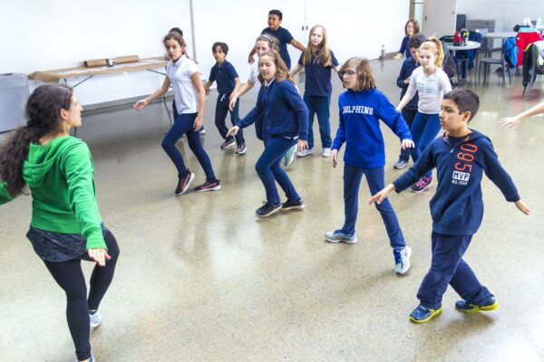 A group of students and teacher dancing in a classroom