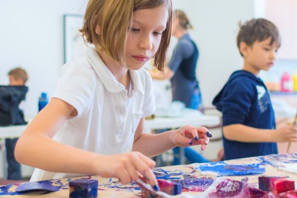 A student painting an artwork in a classroom