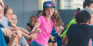 A student dancing wearing a Blue Jays baseball cap in a classroom