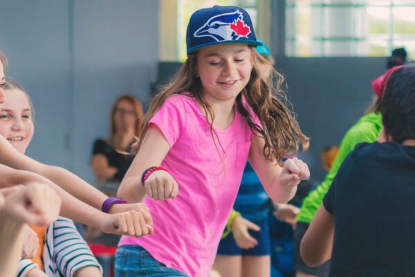 A student dancing wearing a Blue Jays baseball cap in a classroom