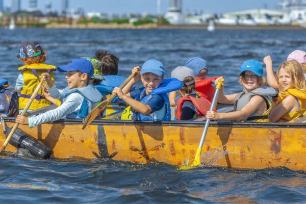 Group of kids paddling their canoe on the water