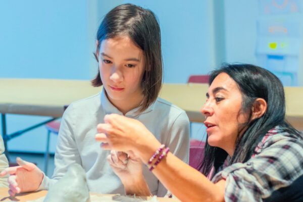 An instructor teaching a student how to build a sculpture craft