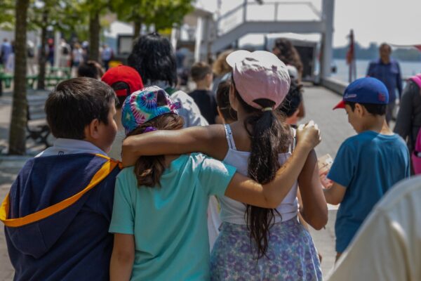 Group of kids hugging and walking outside by the water