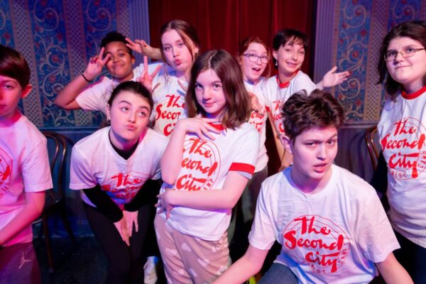 A group of kids posing for the camera on stage