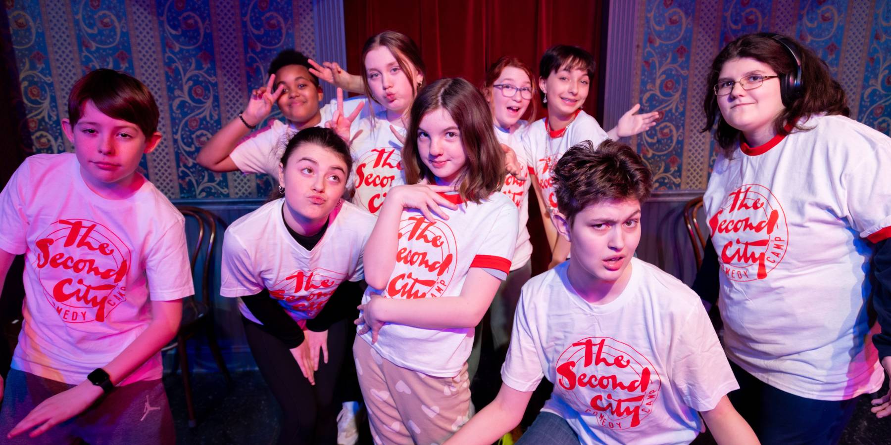 A group of kids posing for the camera on stage