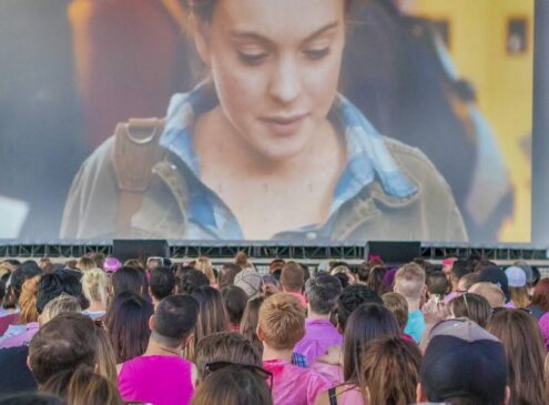 Audience watching a movie at an outdoor concert stage.