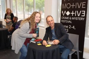 Book fan posing for a photo with an author at a festival.