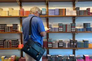 A man browsing a bookstore and reading a book while standing.