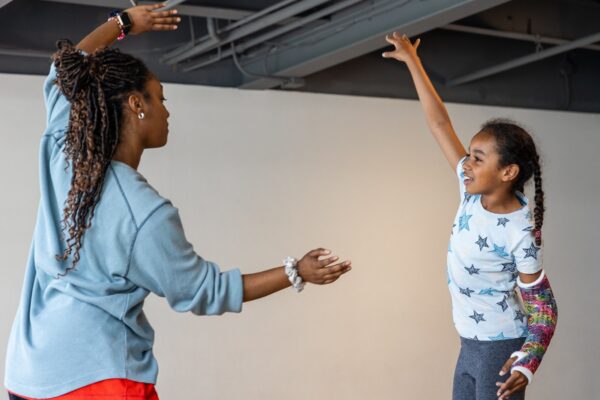 A dance instructor teaching a kid to dance