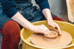 Two hands working on a ceramic piece in a class