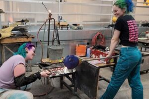 Two women glassblowing in a studio