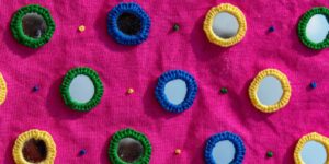 An close-up shot of a bright pink fabric with embroidered circle mirrors