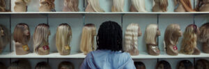 A young child standing looking at a shelf of mannequins facing away from the camera.