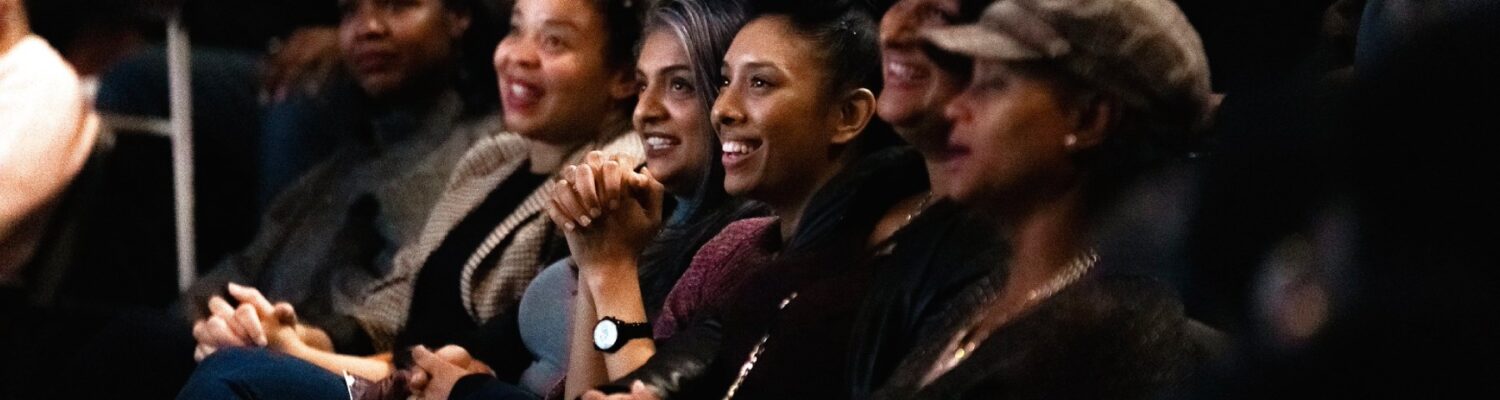 Women sitting in a theatre smiling and clapping