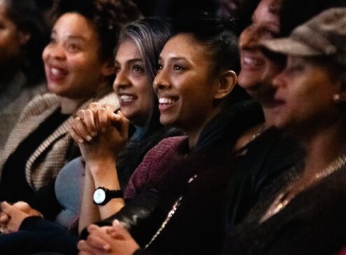 Women sitting in a theatre smiling and clapping