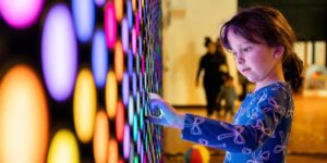 A little girl interacting with a light installation indoors