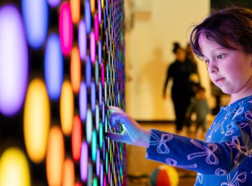 A little girl interacting with a light installation indoors