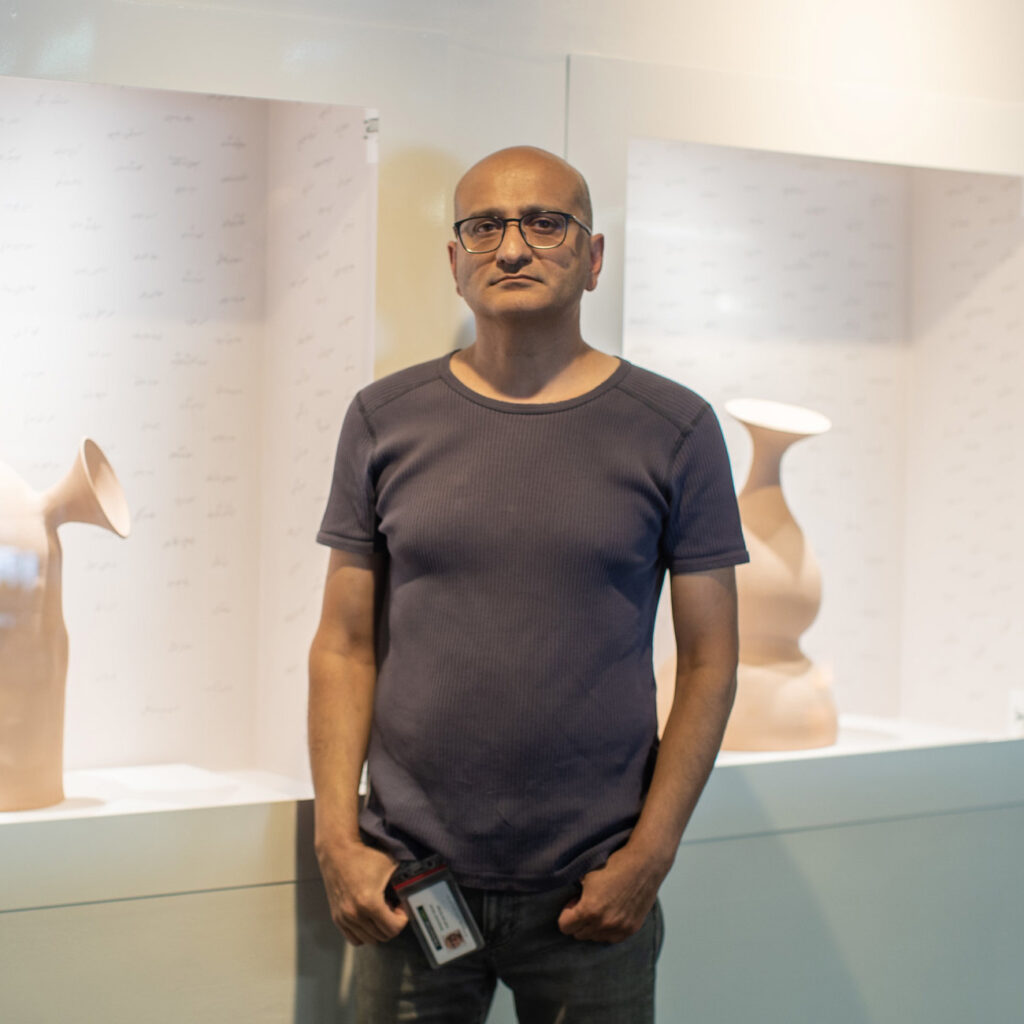 Mohammad standing in front of a display of his artwork