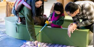 Two parents playing with their child fishing at a pretend pond