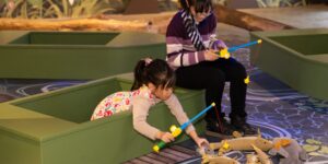 A girl with her mom at a pretend fishing pond