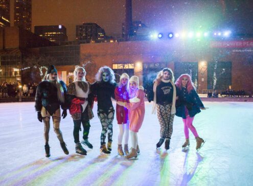 A group of people skating on an outdoor ice rink.