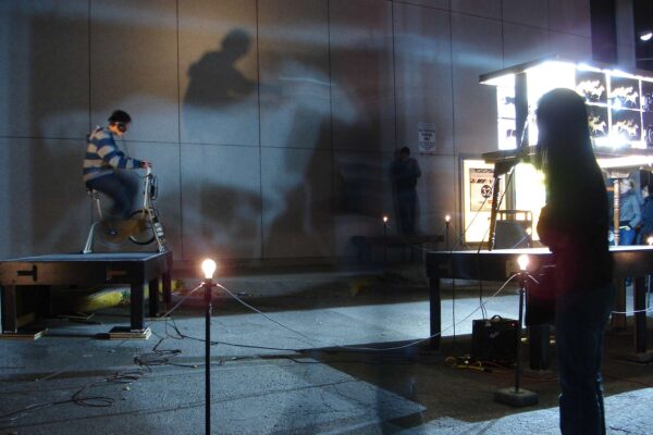 Two people participating in an interactive art installation in a dark setting