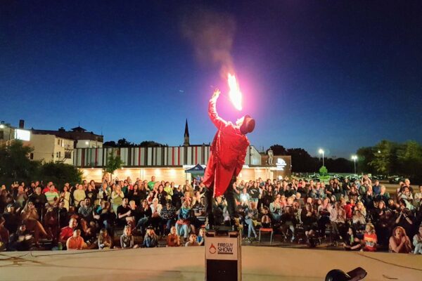 A performer doing a fire show in front of an outdoor crowd.