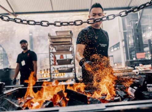 Two cooks grilling meat at an outdoor market