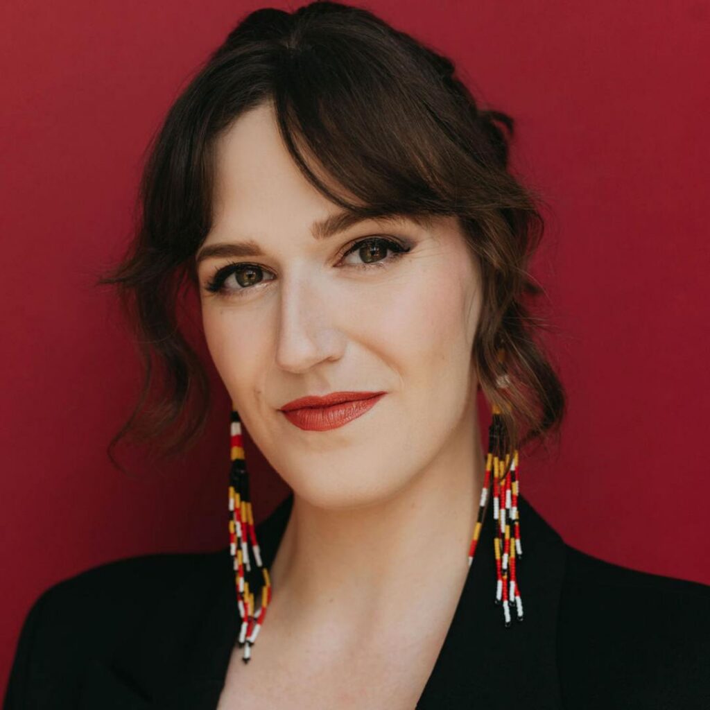 A headshot of a womman posing for the camera against a red background
