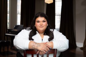 Woman wearing white sitting on a chair posing for the camera