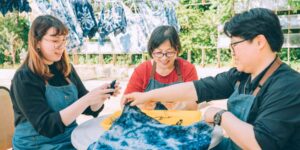 Group of three people doing a dye craft activity outside.