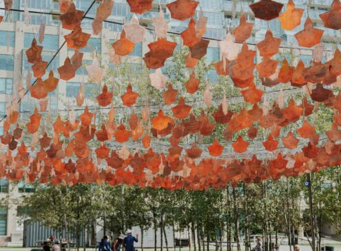 A colourful outdoor installation of copper leaves suspended in the air at Harbourfront Centre