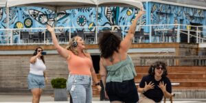 A group of women dancing outdoors wearing headphones
