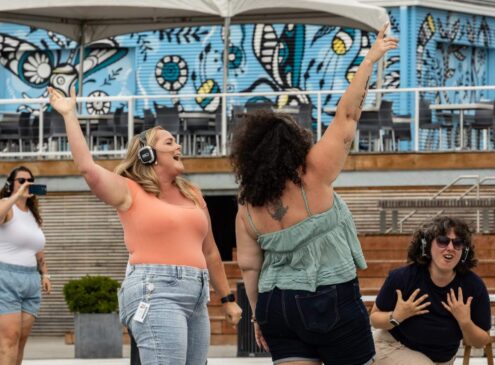 A group of women dancing outdoors wearing headphones